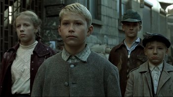 Movie still from “Downfall” (2004), directed by Oliver Hirschbiegel – A young boy wearing a coat and a hat; Close Up shot, Over the shoulder angle