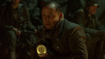 Movie still from “Downfall” (2004), directed by Oliver Hirschbiegel – A man holding a clock while wearing a jacket; Close Up shot, Over the shoulder angle