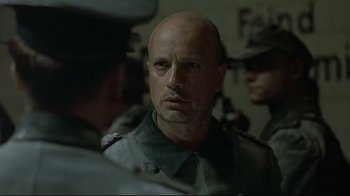Movie still from “Downfall” (2004), directed by Oliver Hirschbiegel – A man with a bald head in a military uniform; Close Up shot, Over the shoulder angle