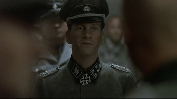 Movie still from “Downfall” (2004), directed by Oliver Hirschbiegel – A man in a military uniform is standing in front of other men; Close Up shot, Over the shoulder angle