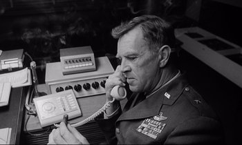 Movie still from “Dr. Strangelove or: How I Learned to Stop Worrying and Love the Bomb” (1964), directed by Stanley Kubrick – An old photo of a man on the phone; Medium shot, Low angle