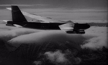 Movie still from “Dr. Strangelove or: How I Learned to Stop Worrying and Love the Bomb” (1964), directed by Stanley Kubrick – A black and white photo of a plane in the sky; Extreme Wide shot, Overhead angle