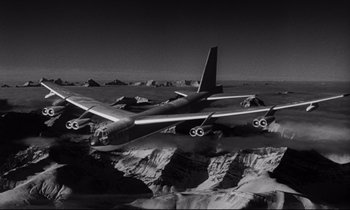 Movie still from “Dr. Strangelove or: How I Learned to Stop Worrying and Love the Bomb” (1964), directed by Stanley Kubrick – An airplane is flying over a mountain range; Extreme Wide shot, Low angle