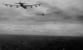 Movie still from “Dr. Strangelove or: How I Learned to Stop Worrying and Love the Bomb” (1964), directed by Stanley Kubrick – A group of planes flying in the sky over a city; Extreme Wide shot, Low angle