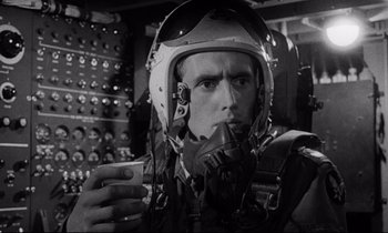Movie still from “Dr. Strangelove or: How I Learned to Stop Worrying and Love the Bomb” (1964), directed by Stanley Kubrick – A man wearing a helmet and holding a cell phone in his hand; Close Up shot, Low angle
