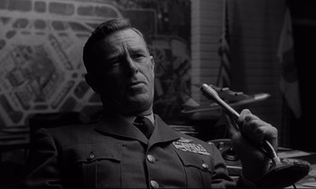 Movie still from “Dr. Strangelove or: How I Learned to Stop Worrying and Love the Bomb” (1964), directed by Stanley Kubrick – An old photo of a man in uniform holding a toothbrush; Close Up shot, Low angle