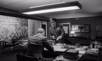 Movie still from “Dr. Strangelove or: How I Learned to Stop Worrying and Love the Bomb” (1964), directed by Stanley Kubrick – An old photo of a man in a military uniform; Medium shot, Low angle