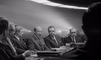 Movie still from “Dr. Strangelove or: How I Learned to Stop Worrying and Love the Bomb” (1964), directed by Stanley Kubrick – A black and white photo of a group of men sitting at a table; Medium shot, Over the shoulder angle