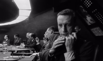 Movie still from “Dr. Strangelove or: How I Learned to Stop Worrying and Love the Bomb” (1964), directed by Stanley Kubrick – Black and white photograph of a man on a cell phone; Close Up shot, Low angle