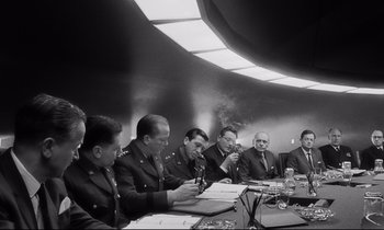 Movie still from “Dr. Strangelove or: How I Learned to Stop Worrying and Love the Bomb” (1964), directed by Stanley Kubrick – A black and white photo of a group of men sitting at a table; Medium shot, Low angle