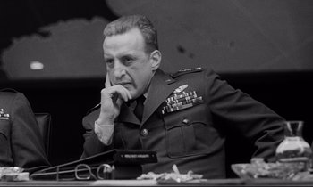 Movie still from “Dr. Strangelove or: How I Learned to Stop Worrying and Love the Bomb” (1964), directed by Stanley Kubrick – An old black and white photo of a man in uniform; Close Up shot, Low angle