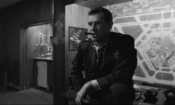 Movie still from “Dr. Strangelove or: How I Learned to Stop Worrying and Love the Bomb” (1964), directed by Stanley Kubrick – A black and white photo of a man smoking a cigar; Medium shot, Low angle
