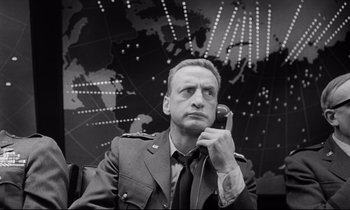 Movie still from “Dr. Strangelove or: How I Learned to Stop Worrying and Love the Bomb” (1964), directed by Stanley Kubrick – A man in a military uniform holding a phone to his ear; Close Up shot, Low angle