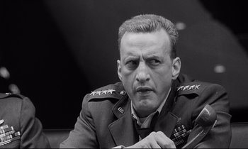 Movie still from “Dr. Strangelove or: How I Learned to Stop Worrying and Love the Bomb” (1964), directed by Stanley Kubrick – An old photo of a man in a military uniform; Close Up shot, Over the shoulder angle