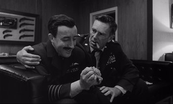 Movie still from “Dr. Strangelove or: How I Learned to Stop Worrying and Love the Bomb” (1964), directed by Stanley Kubrick – Two men in military uniforms are holding a piece of food; Close Up shot, High angle