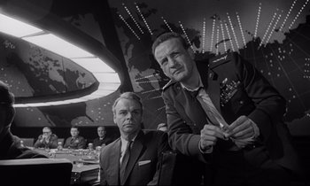 Movie still from “Dr. Strangelove or: How I Learned to Stop Worrying and Love the Bomb” (1964), directed by Stanley Kubrick – A black and white photo of two men in suits and ties; Medium shot, Low angle