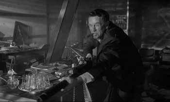 Movie still from “Dr. Strangelove or: How I Learned to Stop Worrying and Love the Bomb” (1964), directed by Stanley Kubrick – An old photo of a man smoking a pipe and playing a piano; Medium shot, Low angle