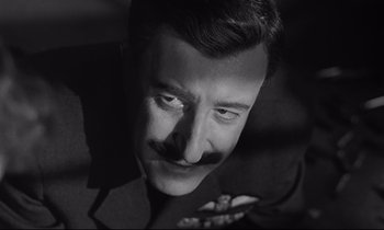 Movie still from “Dr. Strangelove or: How I Learned to Stop Worrying and Love the Bomb” (1964), directed by Stanley Kubrick – A black and white photo of a man with a mustache; Close Up shot, Low angle