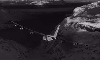 Movie still from “Dr. Strangelove or: How I Learned to Stop Worrying and Love the Bomb” (1964), directed by Stanley Kubrick – An airplane flying over a snowy mountain range; Extreme Wide shot, Overhead angle