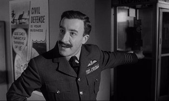 Movie still from “Dr. Strangelove or: How I Learned to Stop Worrying and Love the Bomb” (1964), directed by Stanley Kubrick – An old photo of a man in a military uniform; Medium shot, Low angle