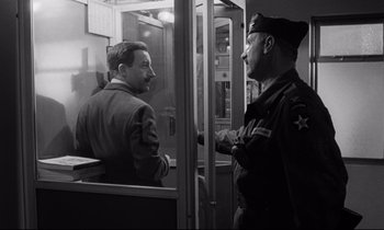 Movie still from “Dr. Strangelove or: How I Learned to Stop Worrying and Love the Bomb” (1964), directed by Stanley Kubrick – Two men are talking to each other in an old photo; Medium shot, Low angle