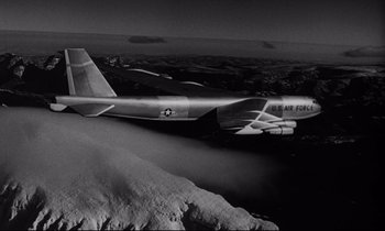 Movie still from “Dr. Strangelove or: How I Learned to Stop Worrying and Love the Bomb” (1964), directed by Stanley Kubrick – An air force jet flying over a mountain range; Wide shot, Low angle