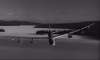 Movie still from “Dr. Strangelove or: How I Learned to Stop Worrying and Love the Bomb” (1964), directed by Stanley Kubrick – An airplane is flying low over a body of water; Extreme Wide shot, Low angle