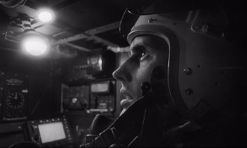 Movie still from “Dr. Strangelove or: How I Learned to Stop Worrying and Love the Bomb” (1964), directed by Stanley Kubrick – A man wearing a helmet is sitting in the cockpit of an airplane; Close Up shot, Low angle