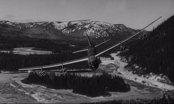 Movie still from “Dr. Strangelove or: How I Learned to Stop Worrying and Love the Bomb” (1964), directed by Stanley Kubrick – An airplane is flying over a snowy mountainous area; Extreme Wide shot, Low angle