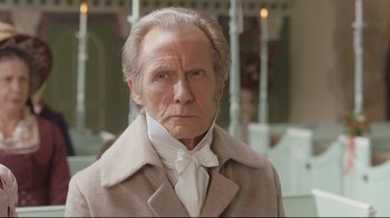 Movie still from “Emma.” (2020), directed by Autumn de Wilde – An old man in a white shirt and a brown coat; Close Up shot, Over the shoulder angle