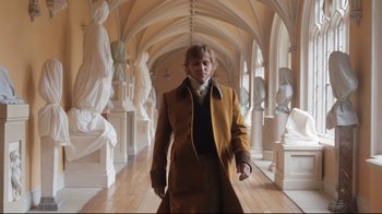 Movie still from “Emma.” (2020), directed by Autumn de Wilde – A man in a long coat walking down a hall way; Wide shot, Low angle