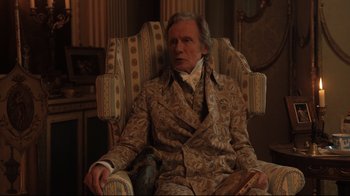 Movie still from “Emma.” (2020), directed by Autumn de Wilde – An older man sitting in a chair in a room; Medium shot, High angle