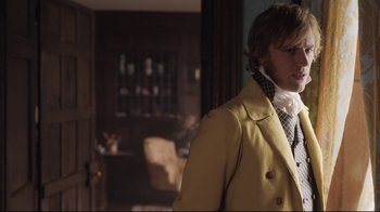 Movie still from “Emma.” (2020), directed by Autumn de Wilde – A man in a yellow coat standing in a room; Medium shot, Over the shoulder angle