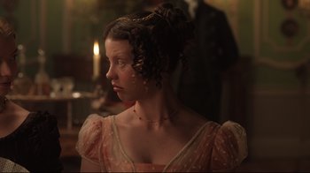 Movie still from “Emma.” (2020), directed by Autumn de Wilde – A woman in a pink dress with a gold chain around her neck; Close Up shot, Over the shoulder angle