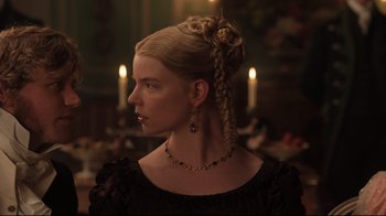 Movie still from “Emma.” (2020), directed by Autumn de Wilde – A woman in a black dress with a long blonde braid in front of candles; Close Up shot, Over the shoulder angle