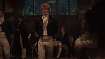 Movie still from “Emma.” (2020), directed by Autumn de Wilde – A man standing in front of a group of people in a room; Medium shot, Over the shoulder angle