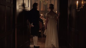 Movie still from “Emma.” (2020), directed by Autumn de Wilde – A man and a woman are standing in front of candles; Medium shot, Over the shoulder angle