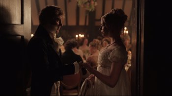 Movie still from “Emma.” (2020), directed by Autumn de Wilde – A man and a woman dressed in period clothing holding hands in front of a crowd; Medium shot, Over the shoulder angle