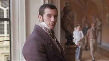 Movie still from “Emma.” (2020), directed by Autumn de Wilde – A man in a suit and tie standing next to a statue; Medium shot, Low angle