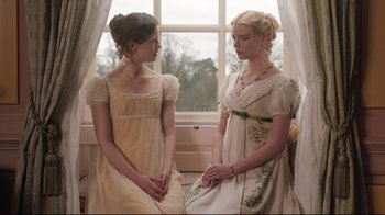 Movie still from “Emma.” (2020), directed by Autumn de Wilde – Two young women dressed in old fashioned dresses; Medium shot, Over the shoulder angle