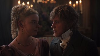 Movie still from “Emma.” (2020), directed by Autumn de Wilde – A man and a woman standing next to each other in front of lights; Close Up shot, Over the shoulder angle