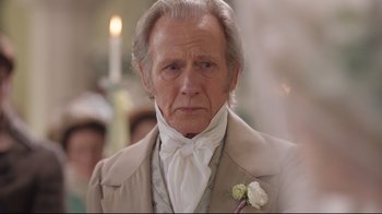 Movie still from “Emma.” (2020), directed by Autumn de Wilde – An older man in a suit and a white rose; Close Up shot, Over the shoulder angle