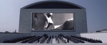Movie still from “Equilibrium” (2002), directed by Kurt Wimmer – An audience is sitting in front of a large screen; Extreme Wide shot, Low angle