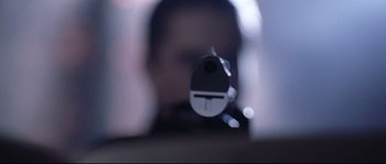 A person's face with a gun pointed at it's side