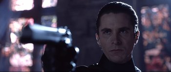 Movie still from “Equilibrium” (2002), directed by Kurt Wimmer – A person with a gun in a dark room; Close Up shot, Low angle