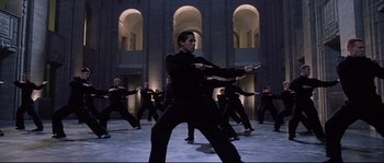 Movie still from “Equilibrium” (2002), directed by Kurt Wimmer – A group of people in black outfits practicing martial arts in an indoor setting; Wide shot, Low angle