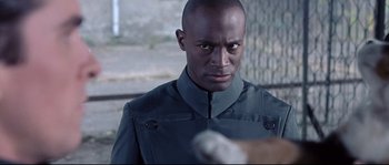 Movie still from “Equilibrium” (2002), directed by Kurt Wimmer – A person wearing a uniform; Close Up shot, Over the shoulder angle