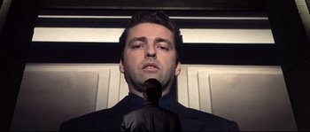 Movie still from “Equilibrium” (2002), directed by Kurt Wimmer – A man standing next to another man in front of a wall; Close Up shot, Low angle