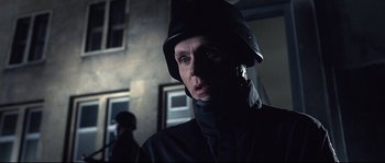 Movie still from “Equilibrium” (2002), directed by Kurt Wimmer – A man wearing a helmet is looking at the camera; Close Up shot, Low angle