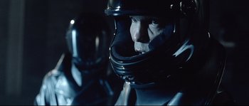 Movie still from “Equilibrium” (2002), directed by Kurt Wimmer – A man wearing a helmet in a dark room; Close Up shot, Over the shoulder angle